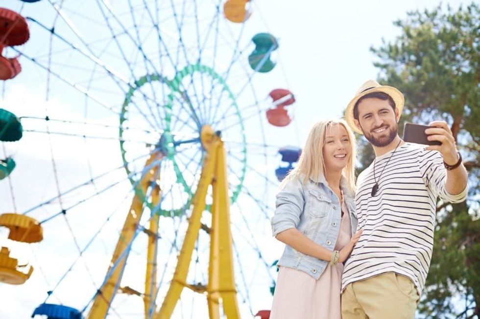 Couple taking a selfie in front of a ferris wheel, The Experience Engine
