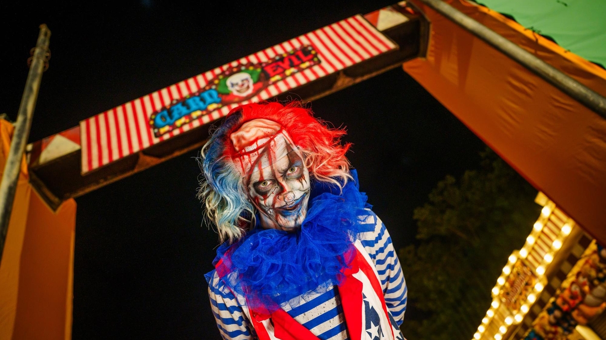 Creepy clown with red, white, and blue attire at a carnival entrance at night at Six Flags Great Adventure