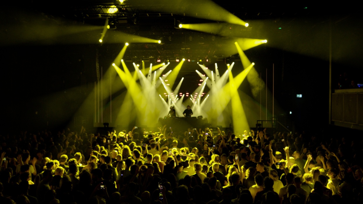 Crowd at a Royksopp concert with a DJ and yellow stage lights, powered by Dimension real-time tech