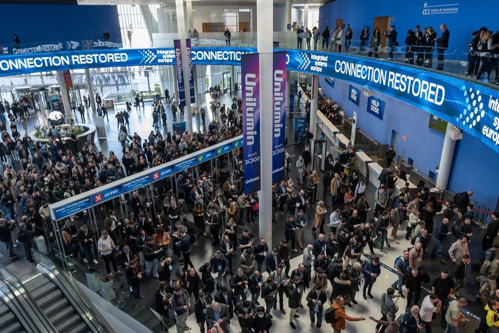 Crowd at a tech convention under "Connection Restored" banners in a spacious hall.