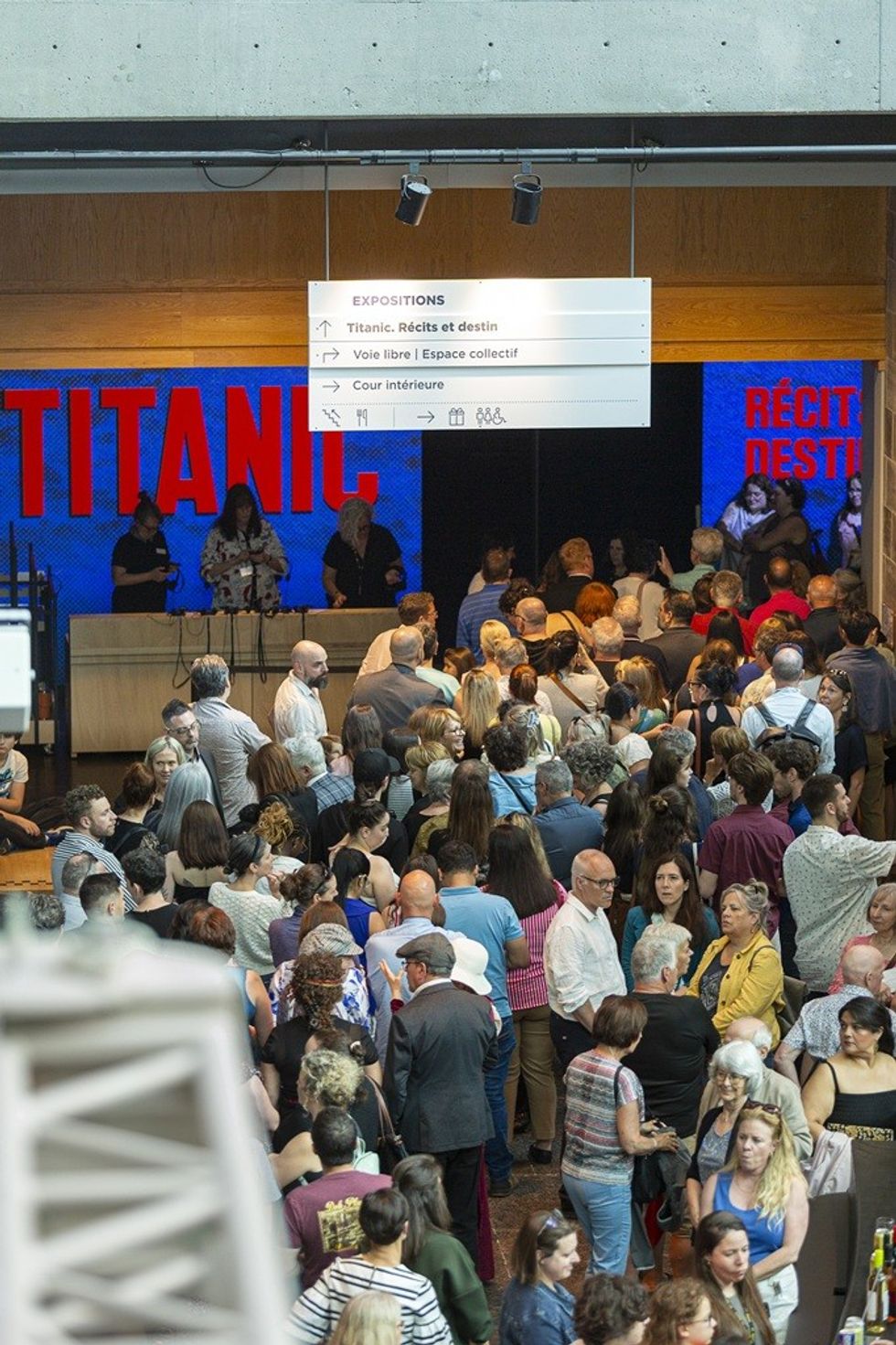 Crowd at Titanic exhibition entrance under signage in a museum lobby.
