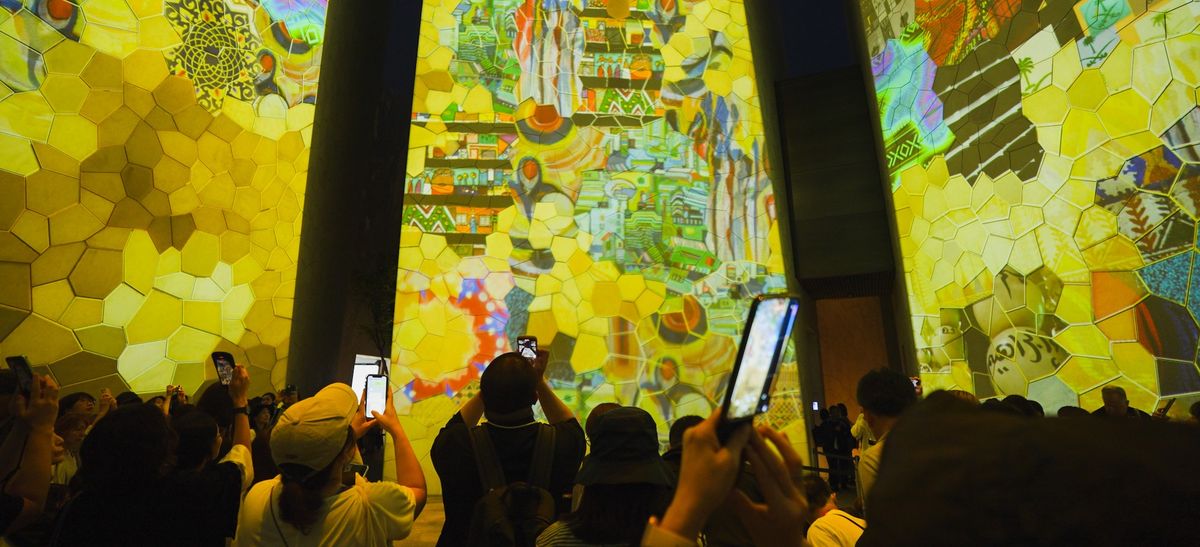 Crowd capturing vibrant projections on mosaic-patterned walls with phones, KSA pavilion Expo 2025 Osaka