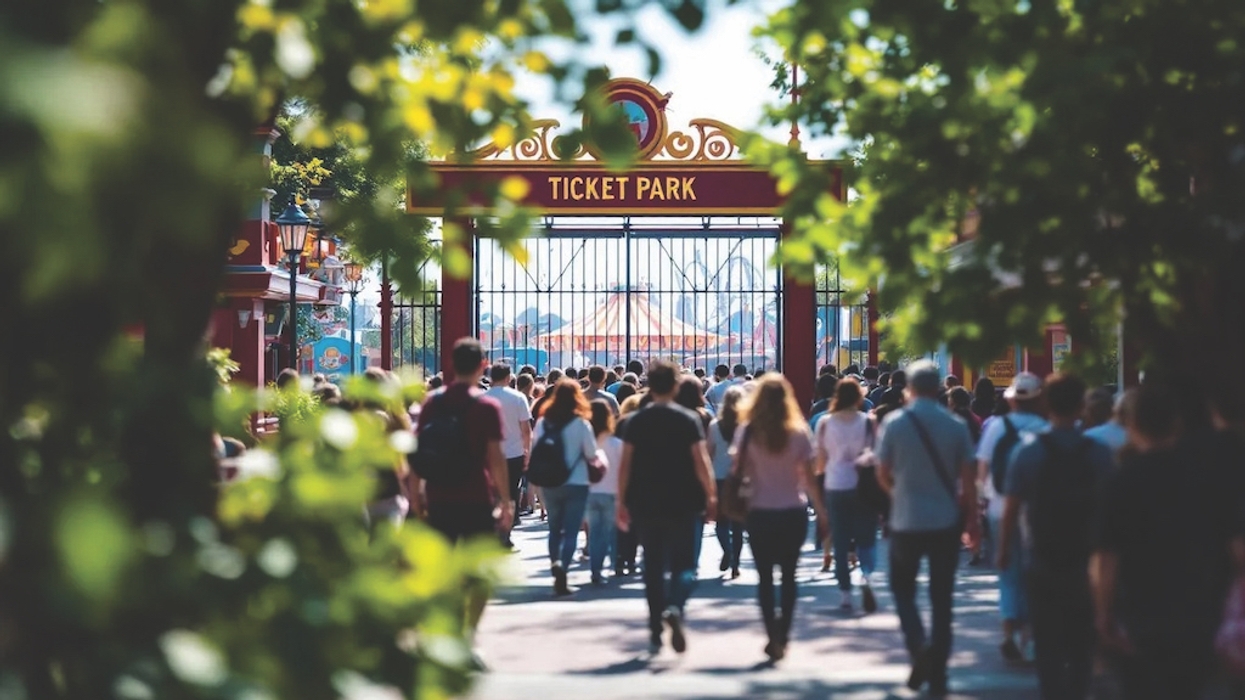 Crowd entering a theme park through the ticket gate, surrounded by trees.