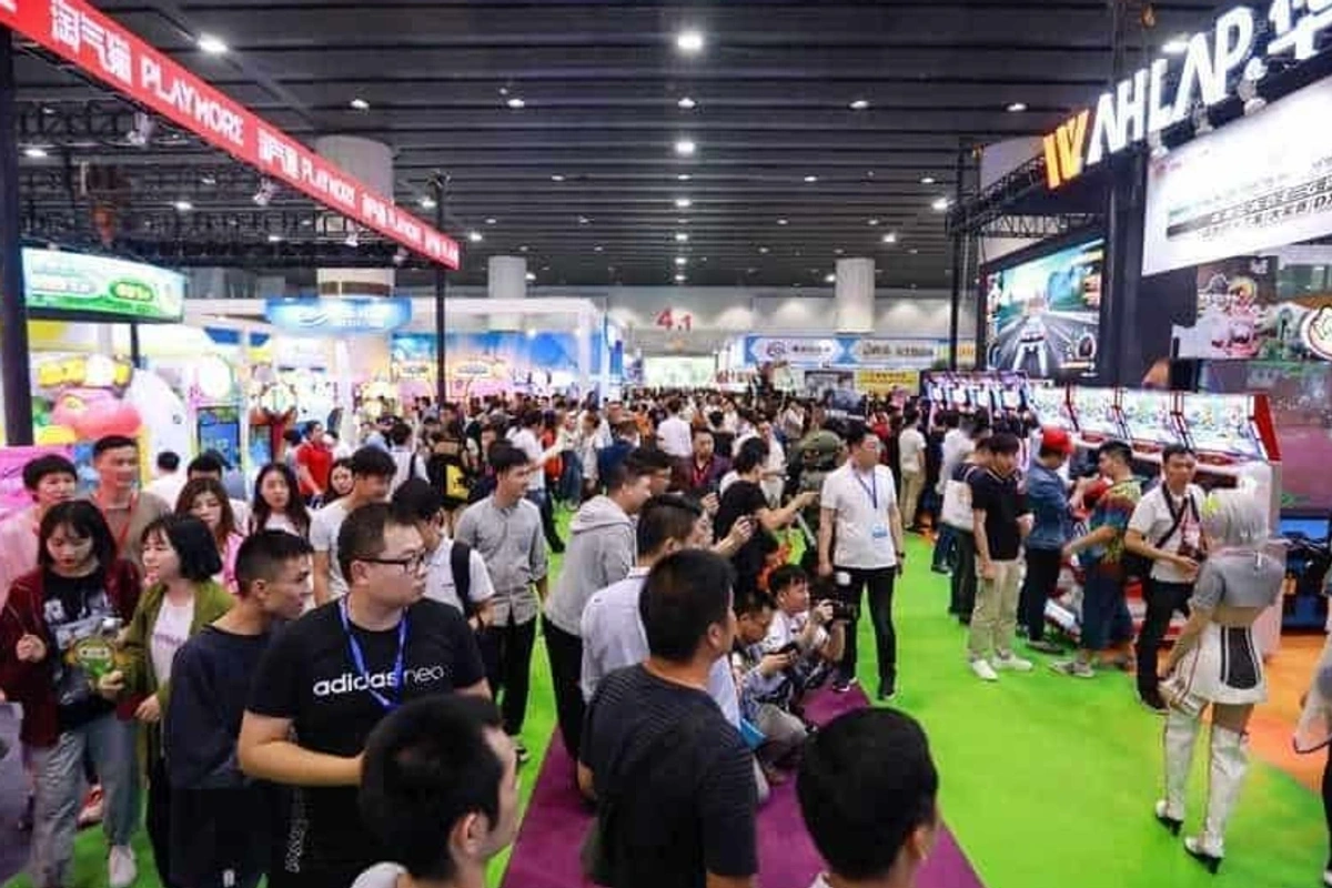 Crowded AAA expo with colorful booths and attendees exploring displays.