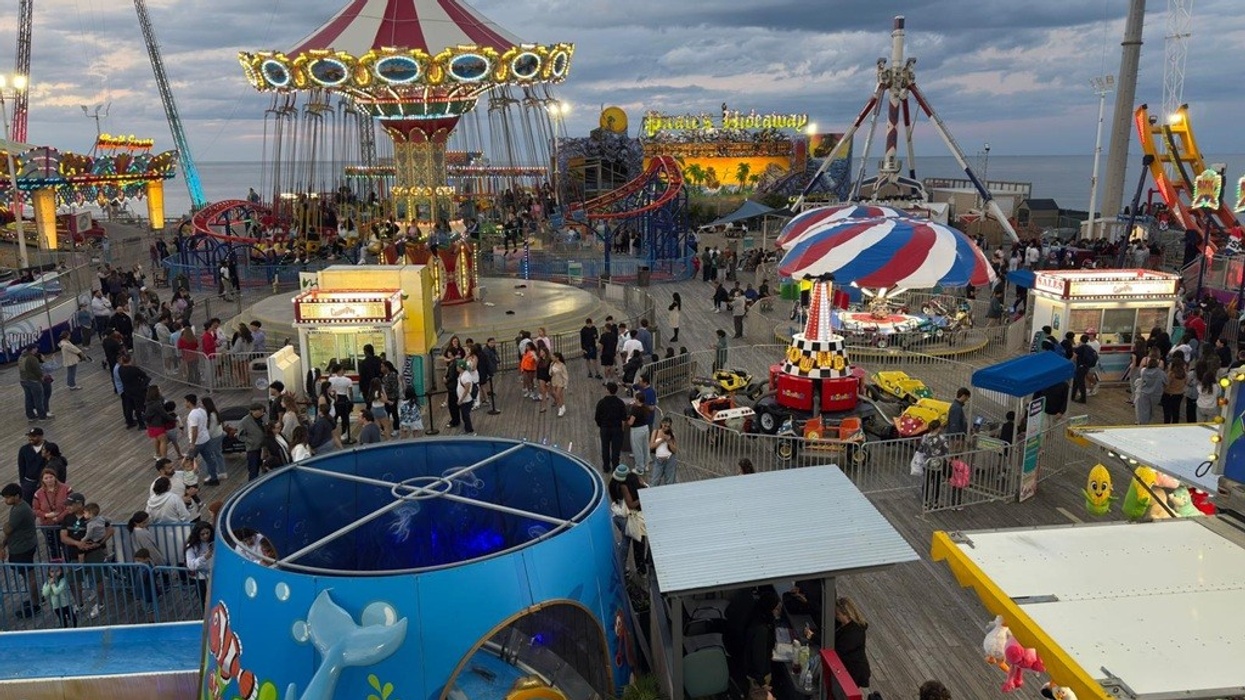 Crowded amusement park with rides and games at sunset.
