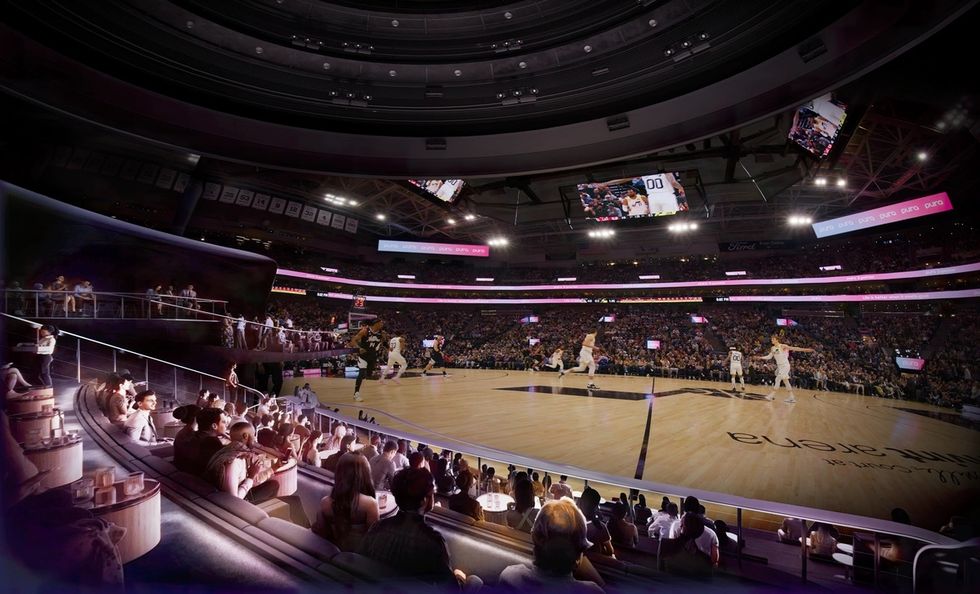 Crowded basketball arena at a Cosm venue with a game in progress, viewed from luxurious seating.