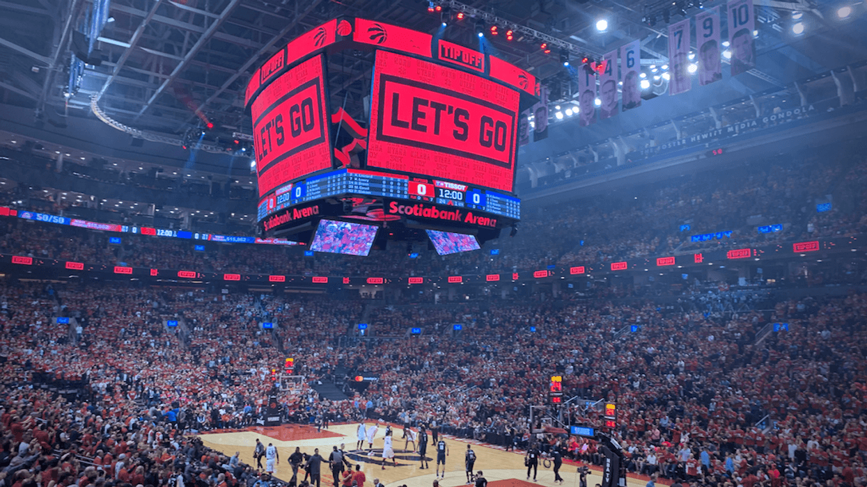 Crowded basketball arena with "Let's Go" displayed on the scoreboard.