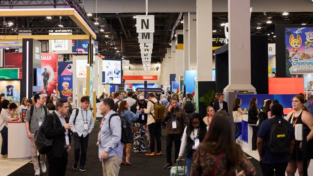 Crowded exhibition hall with people browsing colorful booths at a convention.
