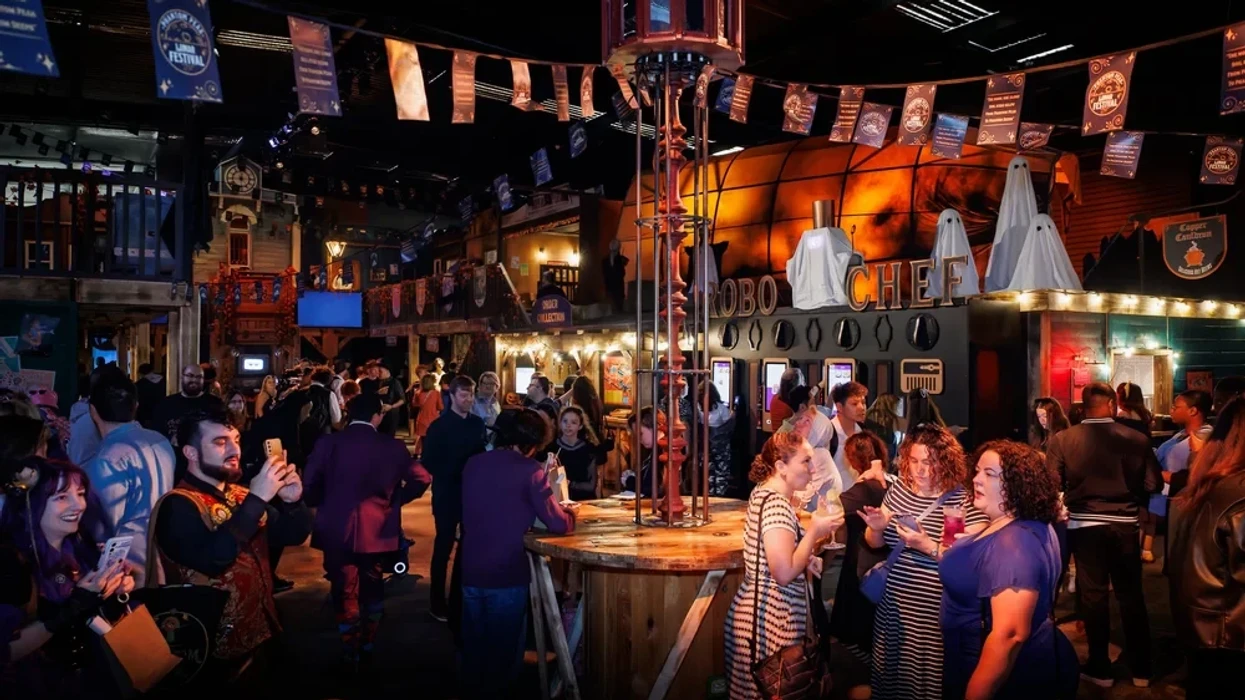 Crowded Halloween-themed indoor event with people socializing and taking photos.