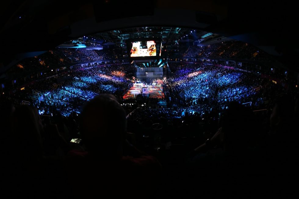 Crowded stadium at the NBA All-Star Game, Toronto 2016, with vibrant lights and large screen, viewed diagonally from above.