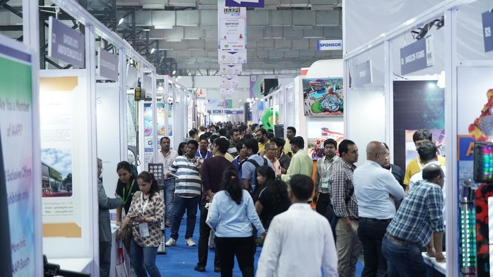 Crowded tech exhibition hall with attendees exploring various booths.