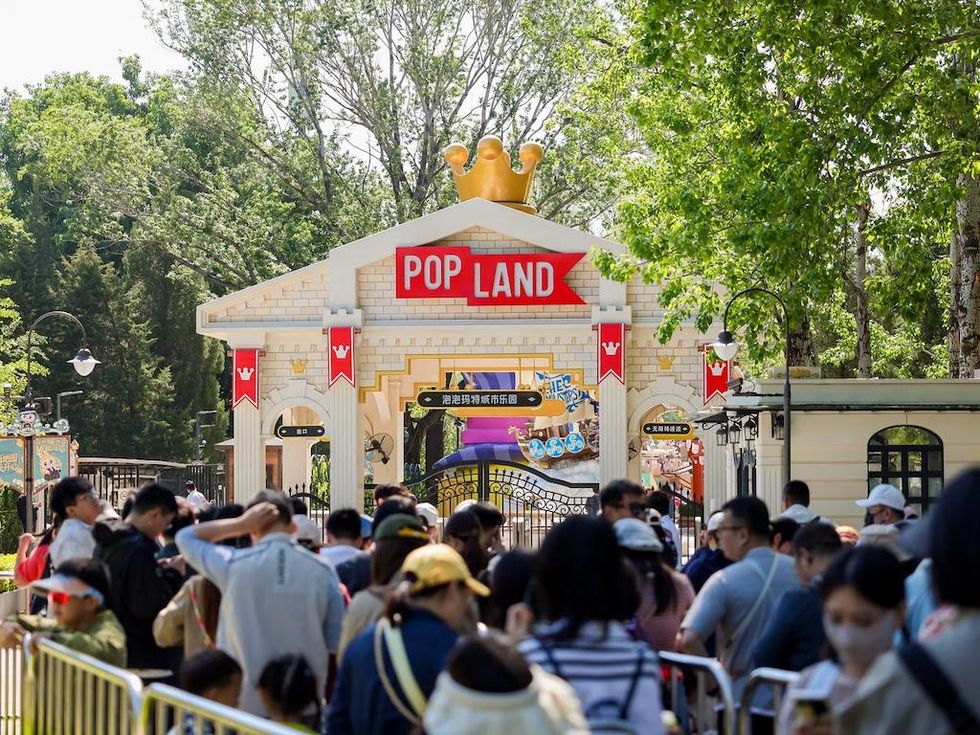 Crowds queue outside the crown-topped entrance to POP LAND amusement park.