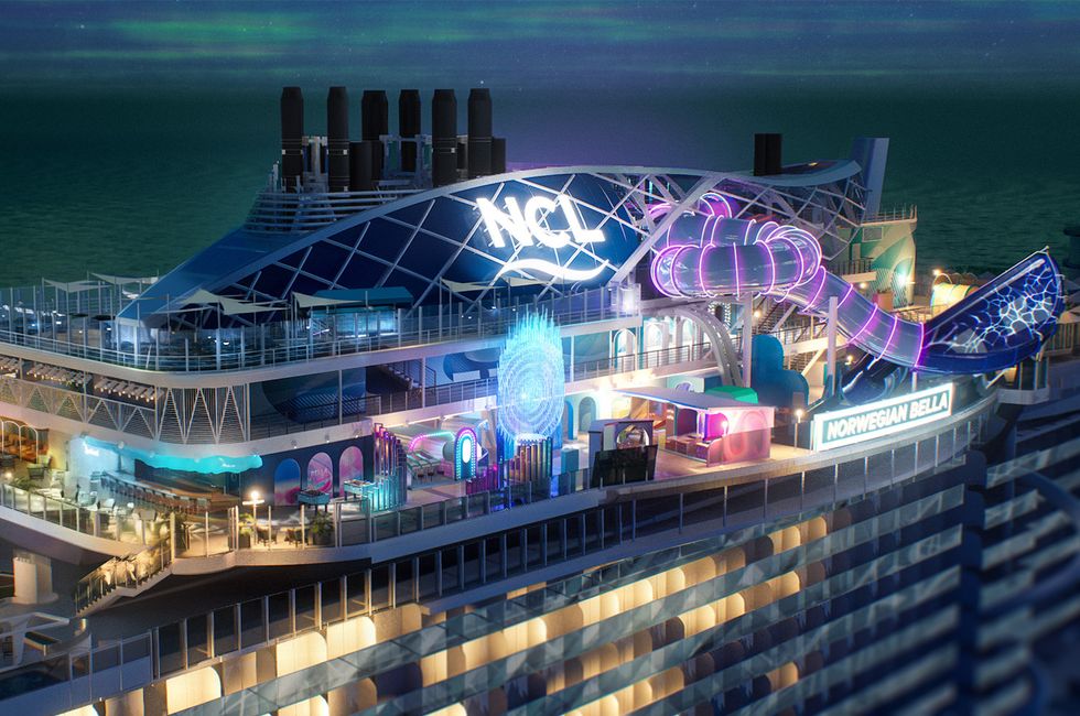 Cruise ship deck at night with colorful lights and water slide.