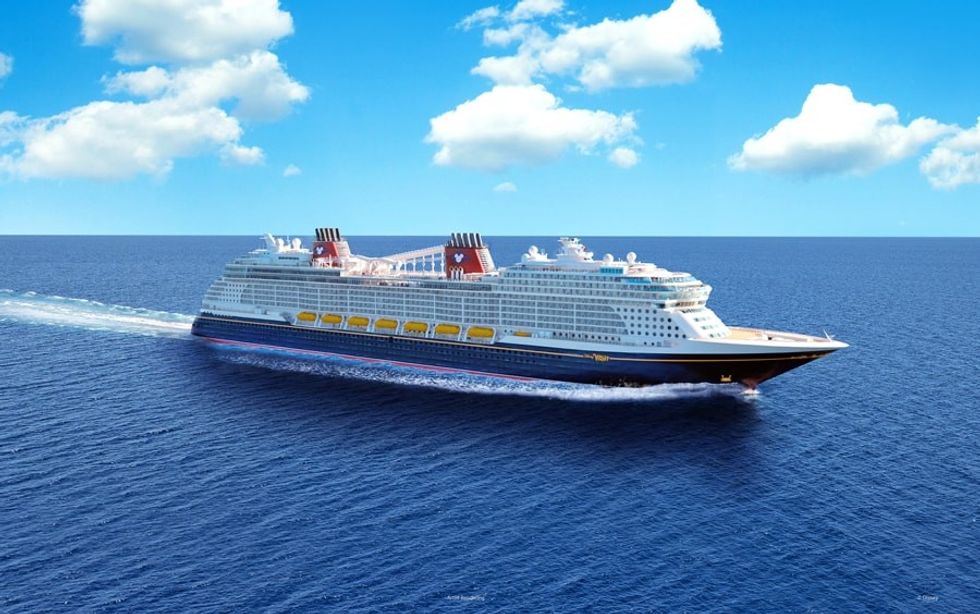 Cruise ship sailing under a blue sky with scattered clouds on a clear day.