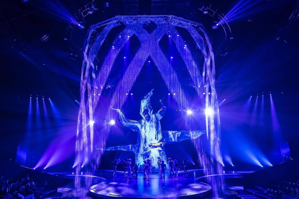 Crystal. Dramatic stage with blue lights and cascading water effects around performers.