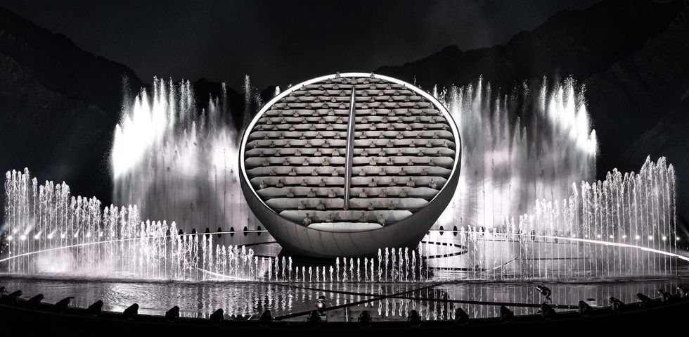 Crystal. Futuristic spherical structure with surrounding water fountains at night.