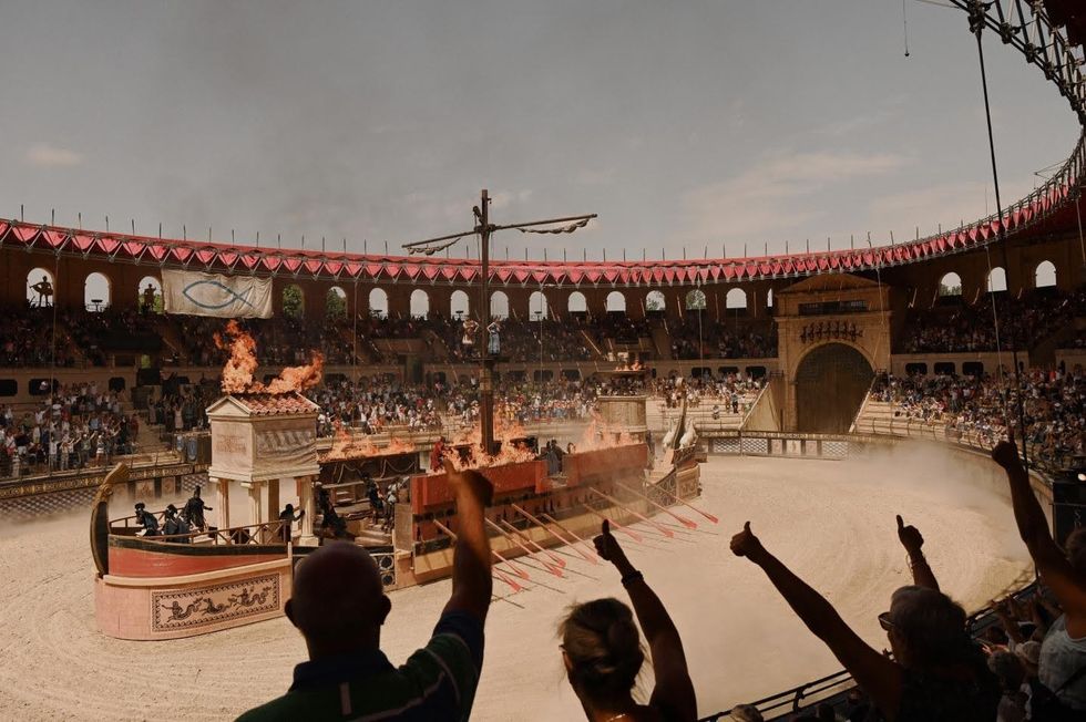 Crytal. Spectators at Puy du Fou watch a burning Roman-style arena performance with chariots and horses.