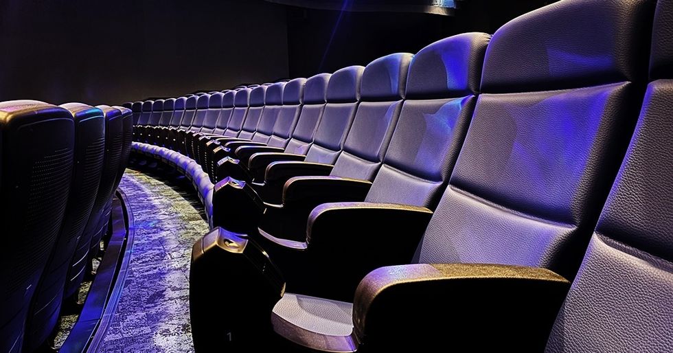 Curved row of empty theater seats under blue lighting.