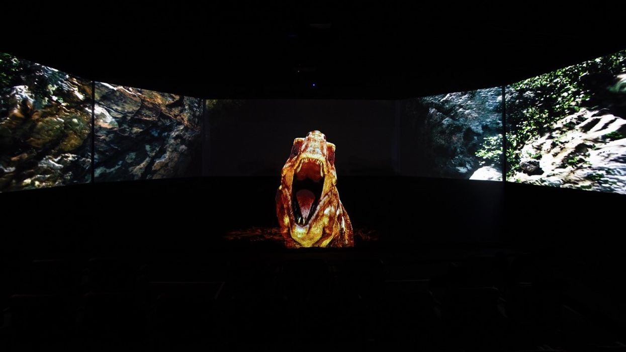 Curved screens showing a roaring dinosaur in a dark room.