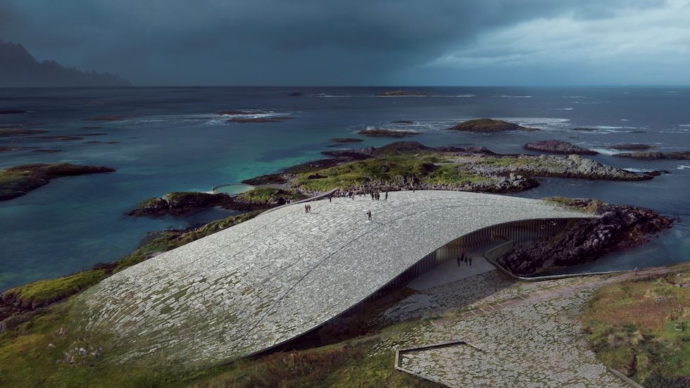 Curved, stone-roofed structure beside rugged coastline and ocean.