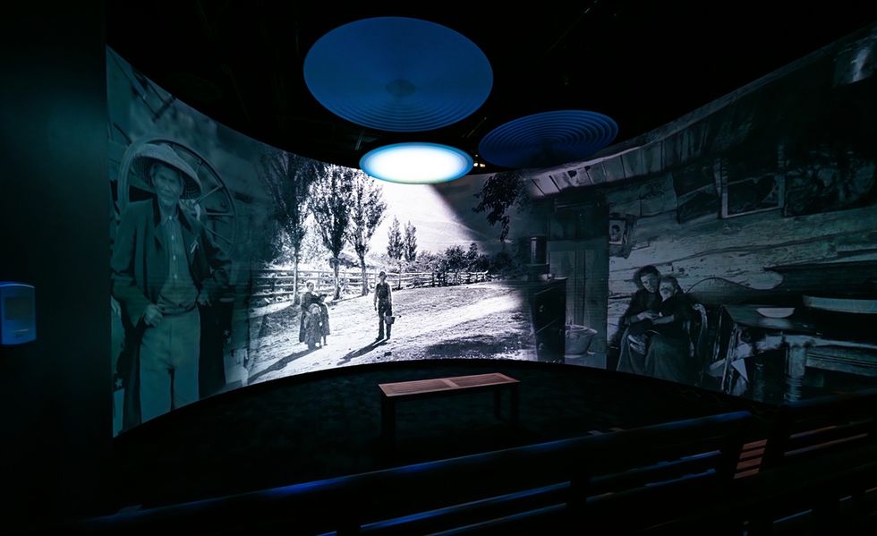 Curved wall projection of historical photos in a dimly lit room with a bench at Museum of Utah