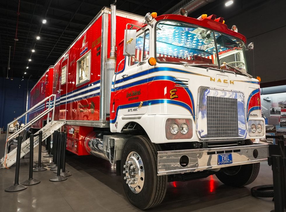 Custom Mack truck with red and blue stripes, displayed indoors with stairs on the side.