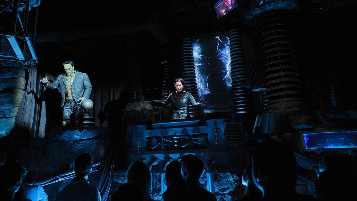 Dark theme show with Frankenstein's monster and scientist on stage, audience watching.