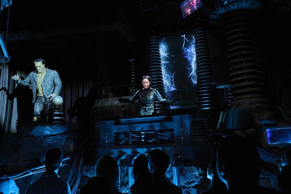 Dark theme show with Frankenstein's monster and scientist on stage, audience watching.