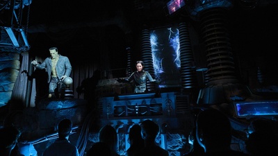 Dark theme show with Frankenstein's monster and scientist on stage, audience watching.