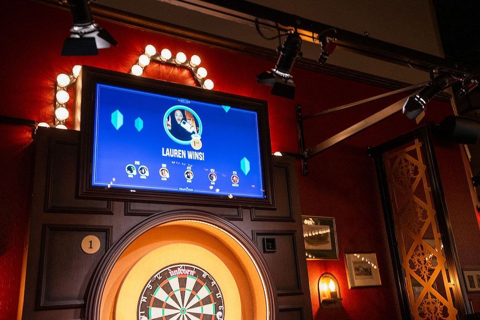 Dartboard game setup with a winning screen displaying "Lauren Wins!" in a lively venue.