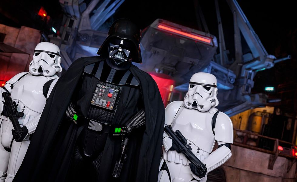 Darth Vader flanked by two stormtroopers in front of a sci-fi backdrop.
