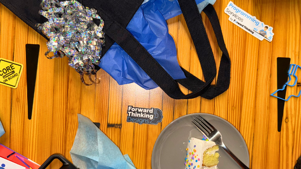 Dessert scene with a slice of cake, tote bag, and promotional items on a wooden table.