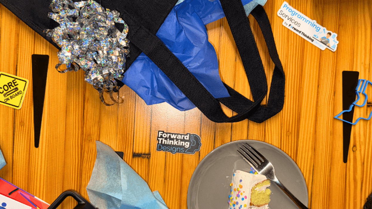 Dessert scene with a slice of cake, tote bag, and promotional items on a wooden table.