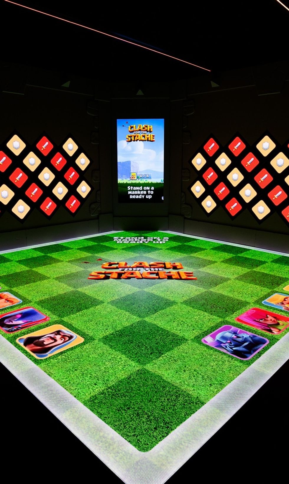 Digital game arena with "Clash for the Stache" theme on screen and floor graphics.