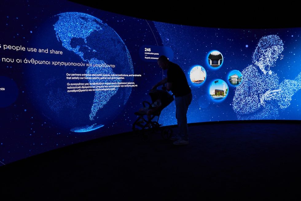 Dimly lit exhibit with digital globe and silhouettes against a blue starry background.