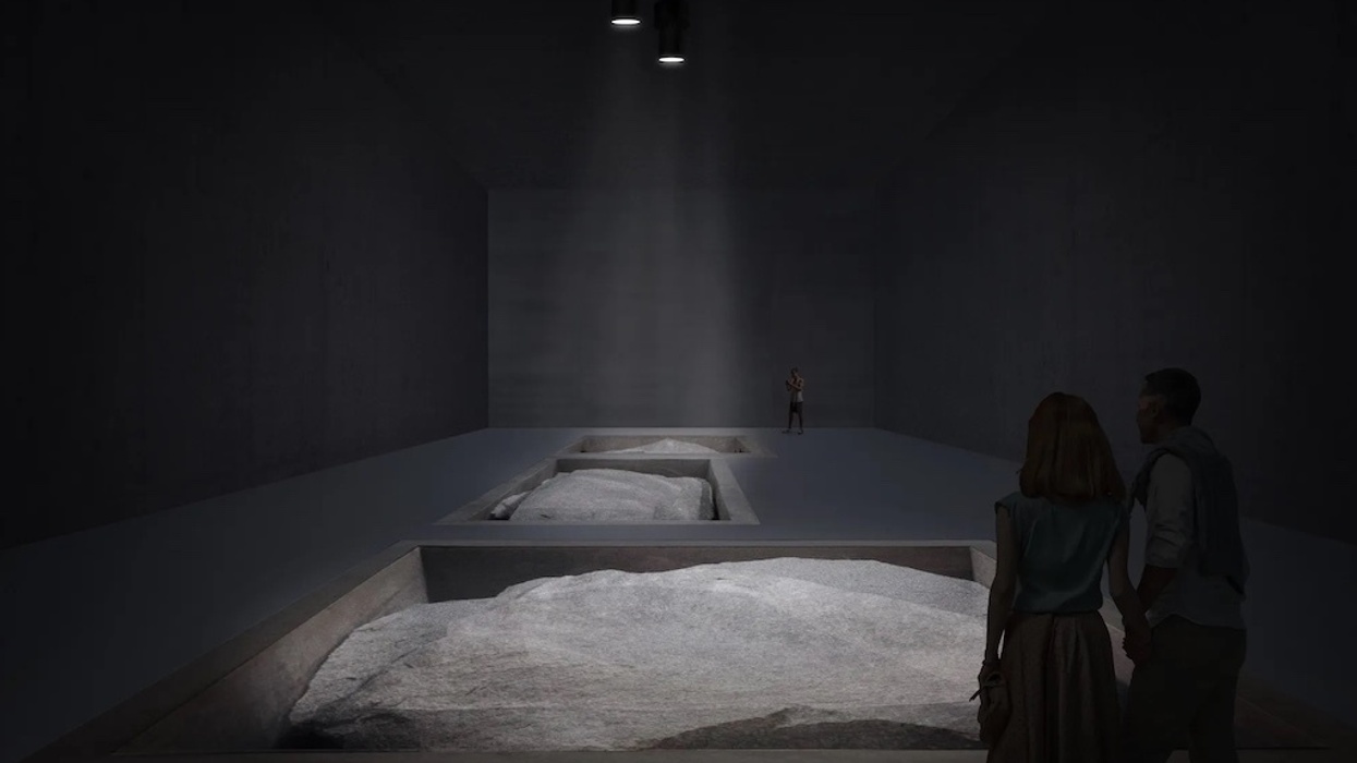 Dimly lit gallery with rock displays and three people observing at Museu Bernardo Paz