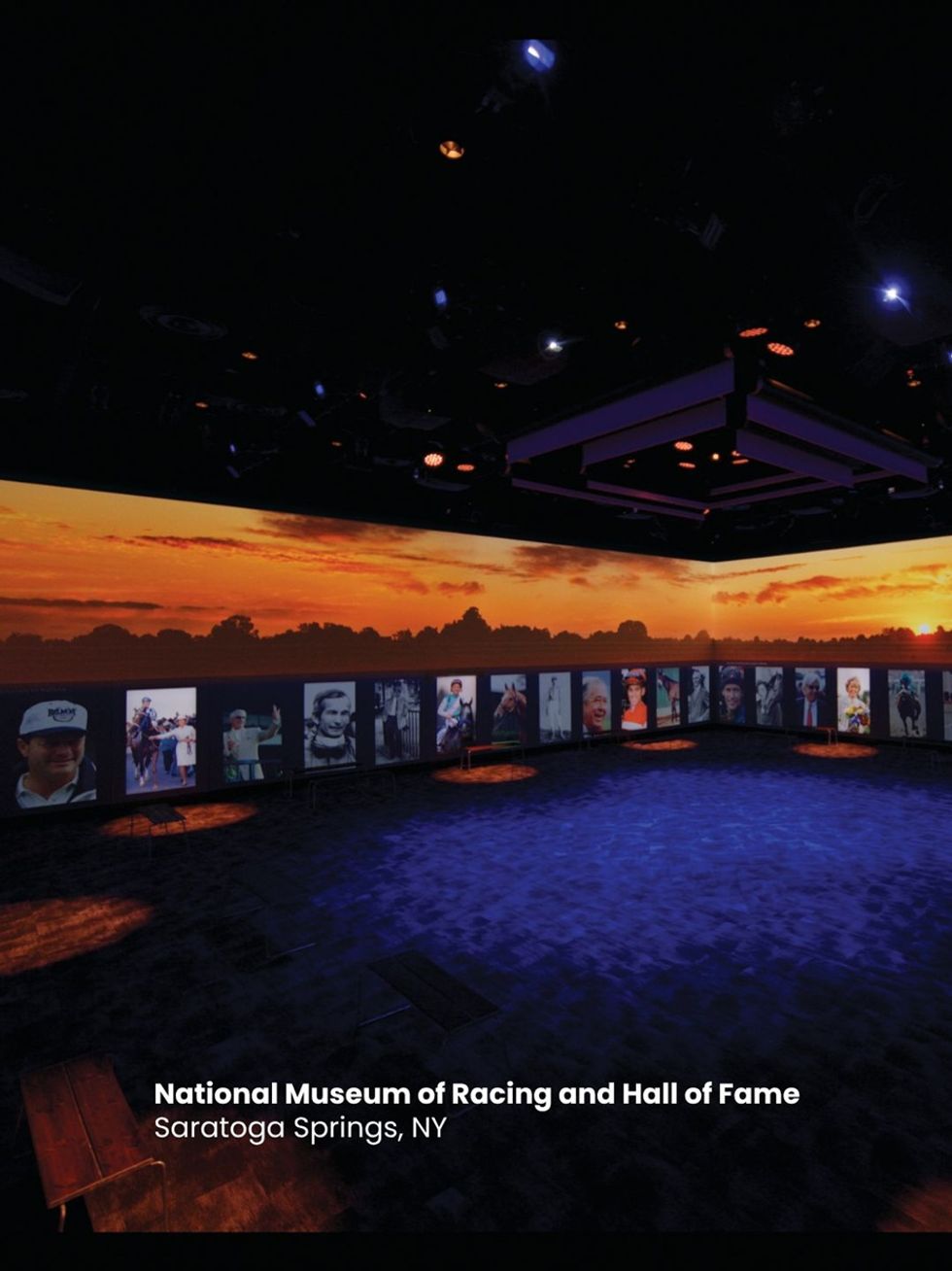 Dimly lit museum room with sunset backdrop and racing portraits, in Saratoga Springs, NY.
