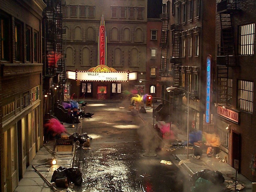 Dimly lit street with neon signs and a movie theater showing "Valley of the Trolls."