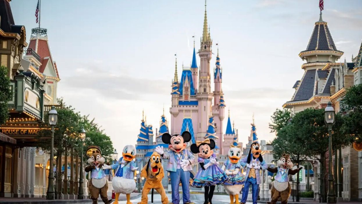 Disney characters pose in front of a castle on Main Street, USA, at a theme park.