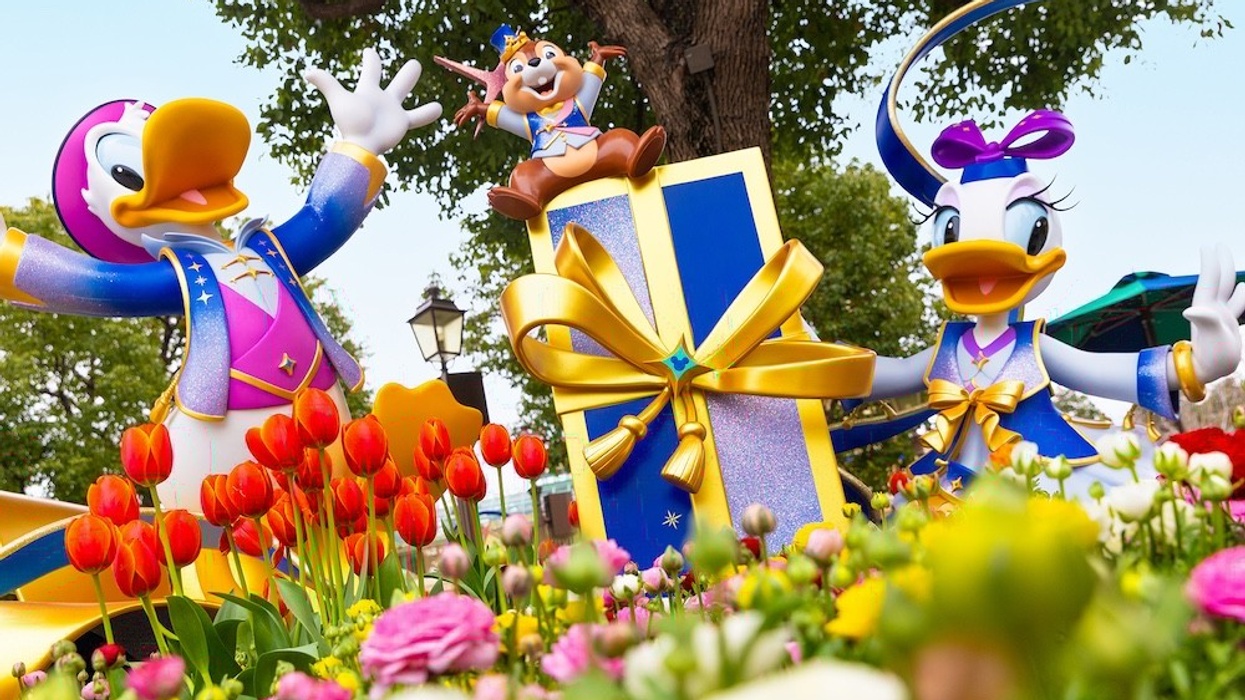 Disney characters with a large gift among colorful flowers.