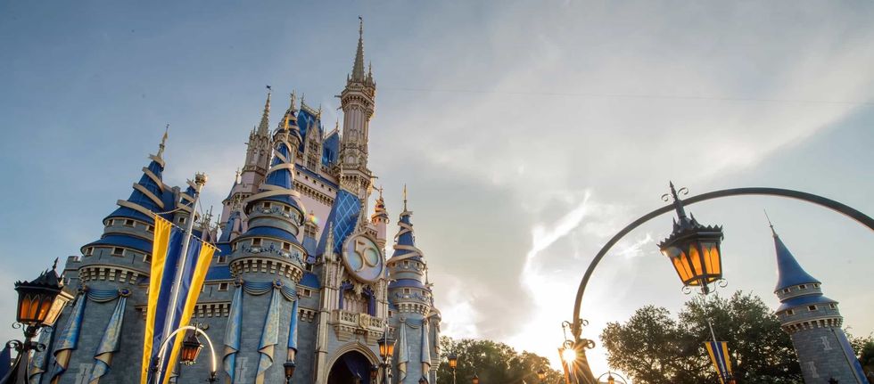 Disney World's Cinderella Castle at sunset with banners and lanterns, celebrating 50th anniversary.