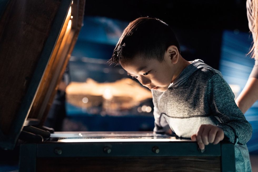 Disney100 Exhibition young visitor looks at interactive