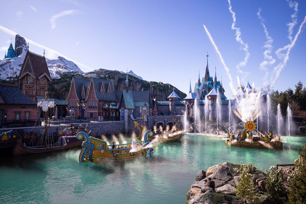 Disneyland Paris with boats, fountains, and castle under a clear blue sky.