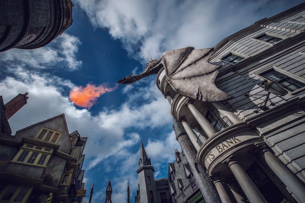 Dragon atop a building breathes fire into the sky on a sunny day at Universal Orlando