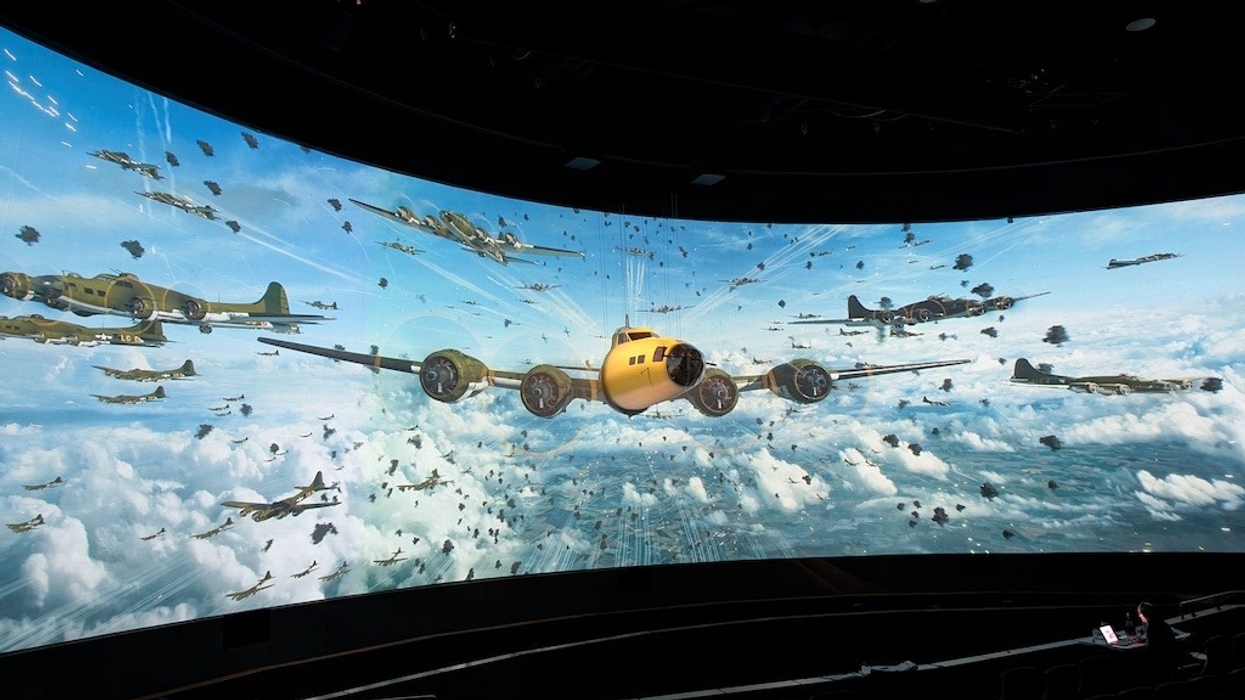 Dramatic flight scene on a large curved panoramic screen in a dark room.