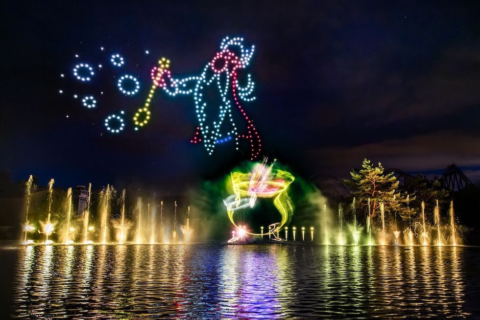 Drone light show above fountains at night, creating colorful images in the sky.