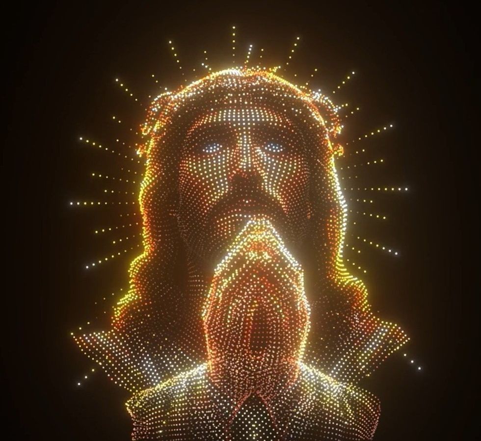 Drone show depicting Jesus praying with radiant halo and clasped hands, glowing in the dark.