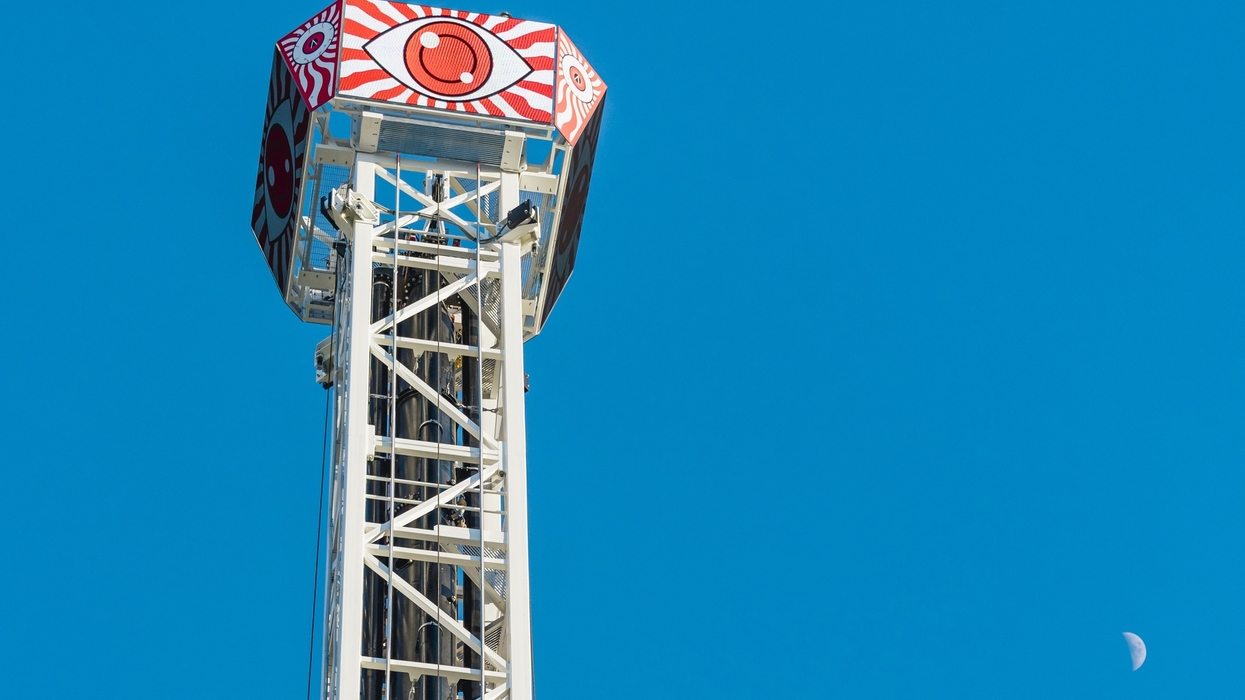 Drop tower ride called Eye Dropper at Area15 with eye design against a clear blue sky and a visible moon.