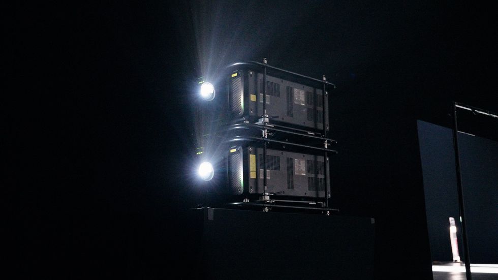 Dual projectors beam bright light in a dark room.