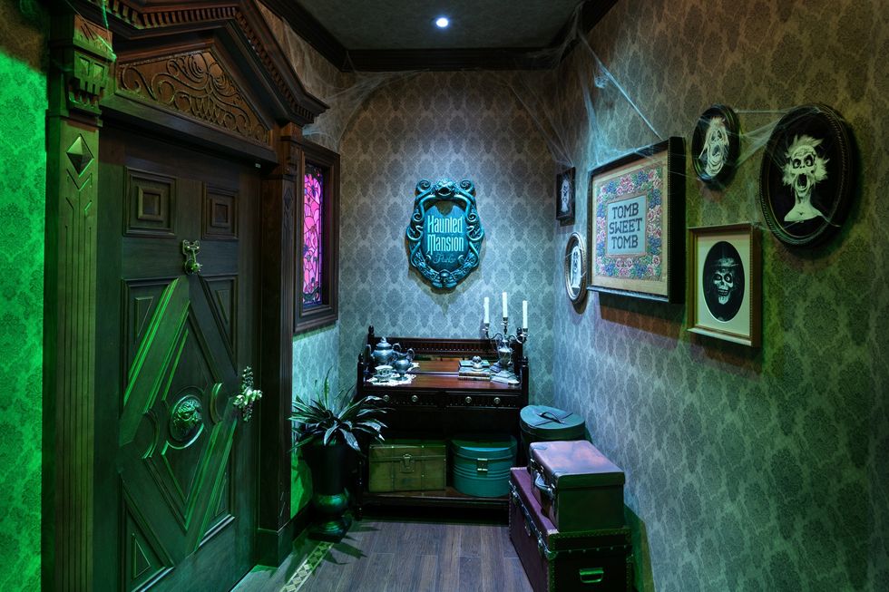 Eerie hallway with spooky decor, green lighting, and a "Haunted Mansion" plaque.